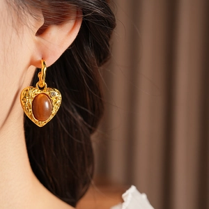 Close-up of vintage resin heart earring with brown gemstone and small diamond detail