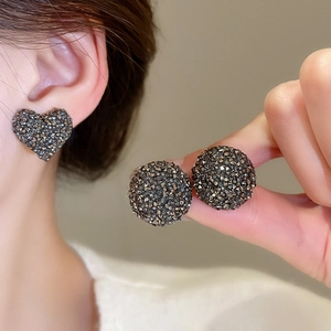 Gros plan de boucles d'oreilles cœur et rondes gris foncé serties de cristaux