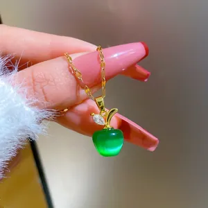 Macro shot of an apple pendant necklace featuring green opal stone and gold leaf detail