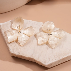 Detail of cream resin flower earrings with marble texture and rhinestone accents