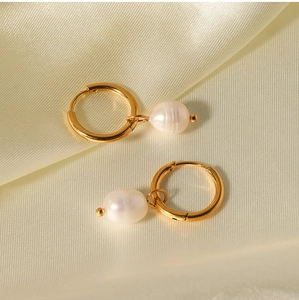 Close-up of gold freshwater pearl earrings resting on elegant golden silk fabric
