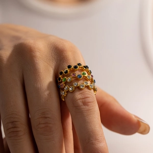 Close-up of stacked colorful zircon rings in gold plating worn on a model's hand