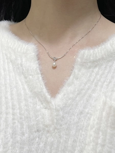 Close-up of a freshwater pearl necklace with silver knot detail on a woman's neck