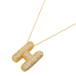 Close-up of golden letter H pendant with shimmering cubic zirconia on a box chain