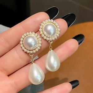 Detail of gold vintage pearl hoop earrings with zircon accents and teardrop pendants