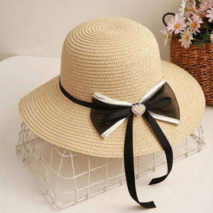 Dettaglio cappello di paglia elegante con fiocco e fibbia in perle e strass a cuore