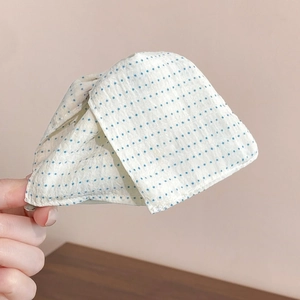 Detail of white triangle hair claw with blue polka dots and soft fabric texture