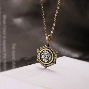Close-up of hexagonal gold pendant with antique silver coin and zircon embellishments
