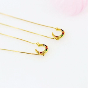 Macro shot of gold box chain necklace with crescent moon pendants and colorful zircons