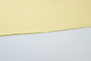 Gros plan sur la texture du tissu en maille jaune clair et les finitions de couture