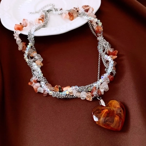 Macro shot of large amber-textured heart pendant on multilayered beaded necklace