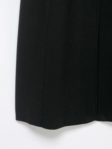 Detail showing the wool blend texture and hem stitching on a black winter coat