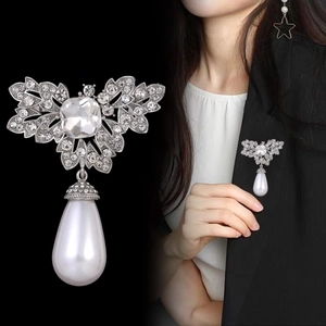 Detailed view of a vintage silver bow brooch with rhinestones and a large pearl pendant