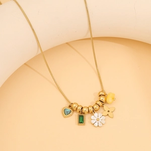 Golden snake chain necklace with floral turquoise and emerald pendants on a beige background