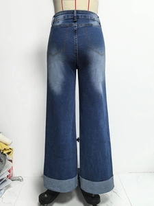 Detail van high waisted jeans met wijde pijpen, achterzakken en vervaagde donkerblauwe wassing