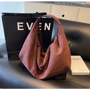 Detail view of a large brown matte faux leather hobo bag on a black sofa