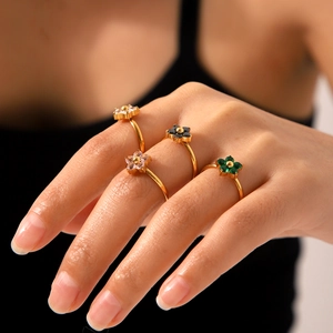 Close-up of elegant gold flower rings with colorful zircon inlays on model fingers