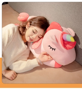 Close-up of soft plush pink unicorn pillow with colorful horn and embroidered sleeping eyes