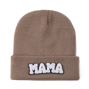 Detailed view of MAMA towel embroidery patch on brown knitted beanie with texture