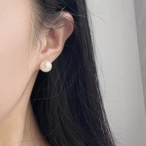 French retro white pearl stud earrings with mirror luster on a female model