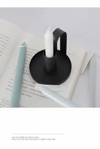 Close-up of matte black iron candle holder with three grey scented candles on a book