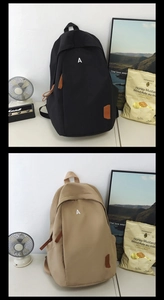 Detail view of black and khaki minimalist backpacks with letter A logo and leather pullers