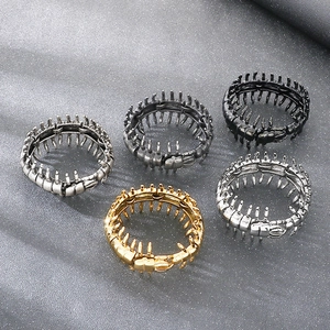 Detail shot of gothic centipede rings in five metallic finishes on a grey textured surface