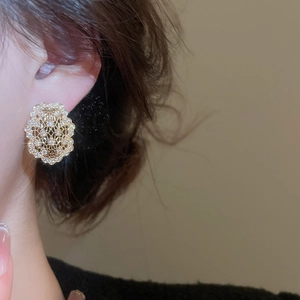 Gros plan d'un mannequin portant des boucles d'oreilles fleur dorées avec des zircons