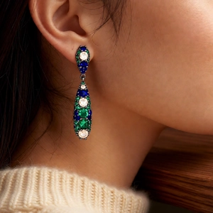 Macro side view of vintage water drop earrings with blue and green zircon on a model