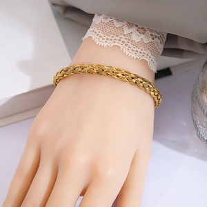 Detailed close-up of a gold braided metal bracelet showing intricate woven texture and knot