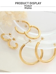 Three pairs of polished gold hollow hoop earrings in different sizes on glass tray