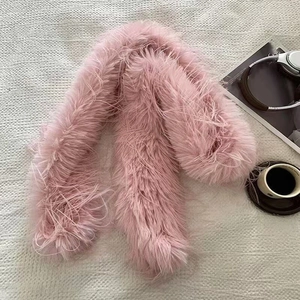 Detail of soft pink faux fur scarf on a table with a magazine and a cup of coffee