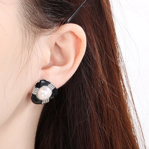 Dettaglio ravvicinato di orecchino vintage in smalto nero con perla su modella