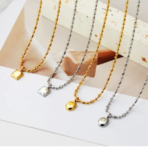 Détail de colliers or et argent avec pendentifs géométriques carrés et ovales sur chaînes à billes
