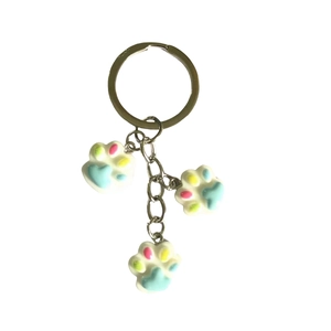 Cute resin cat paw keychain with three colorful charms on a metal ring for bag decoration