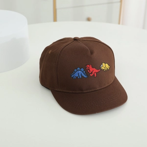 Détail de la broderie de trois dinosaures de dessin animé sur une casquette en coton marron