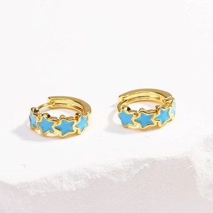 Detailed close-up of gold hoop earrings with five blue enamel star charms on stone
