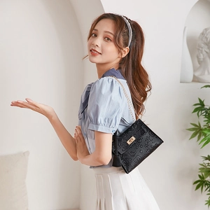 Detail of black crossbody bag with cartoon embossed texture and gold metal chain strap