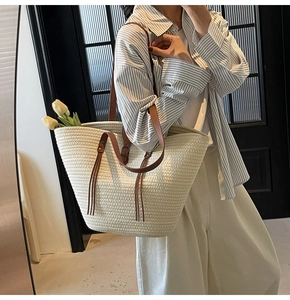 Detailed view of large woven tote bag with leather straps and decorative tassel charm