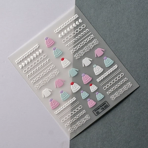 Detailed macro of 5D embossed knit sweater and heart nail art stickers in soft winter colors