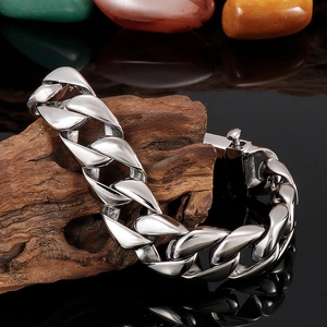 Polished silver stainless steel Cuban link bracelet displayed on natural wood base