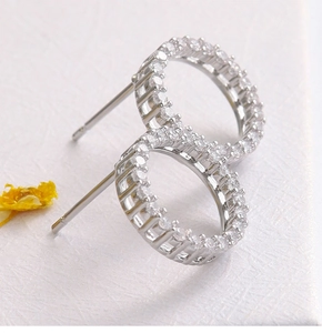 Macro shot of silver-tone hoop earrings with pavé-set zircons on white paper background