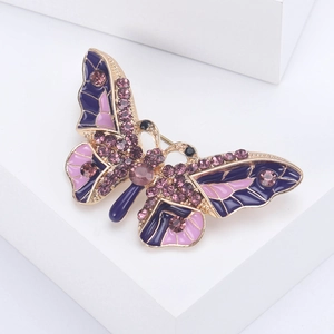Macro detail of golden butterfly brooch with purple rhinestones and enamel wings
