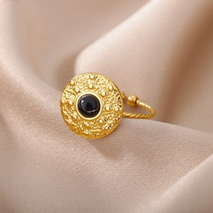 Detailed shot of a vintage gold ring with black stone on champagne silk fabric
