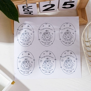 Detail of oval stickers with cat and cake design for festive gift packaging and sealing