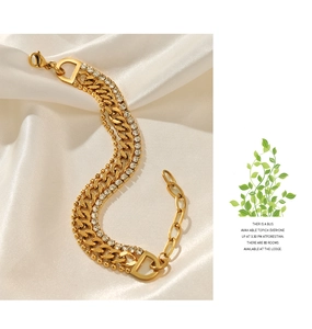 Detailed macro view of triple-layered gold chain bracelet with rhinestones and D-shaped charm