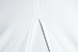 Detailed close-up of the split hem stitching on a white backless sleeveless halter dress