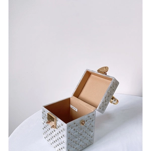Macro view of white acrylic clutch bag with marble finish, rhinestones and golden hardware