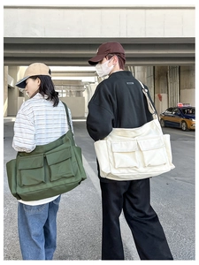 Rear view of models wearing large canvas messenger bags in army green and beige colors