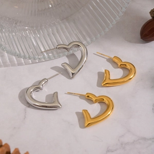 Dettaglio macro di orecchini a cuore lucidi oro e argento su base di marmo